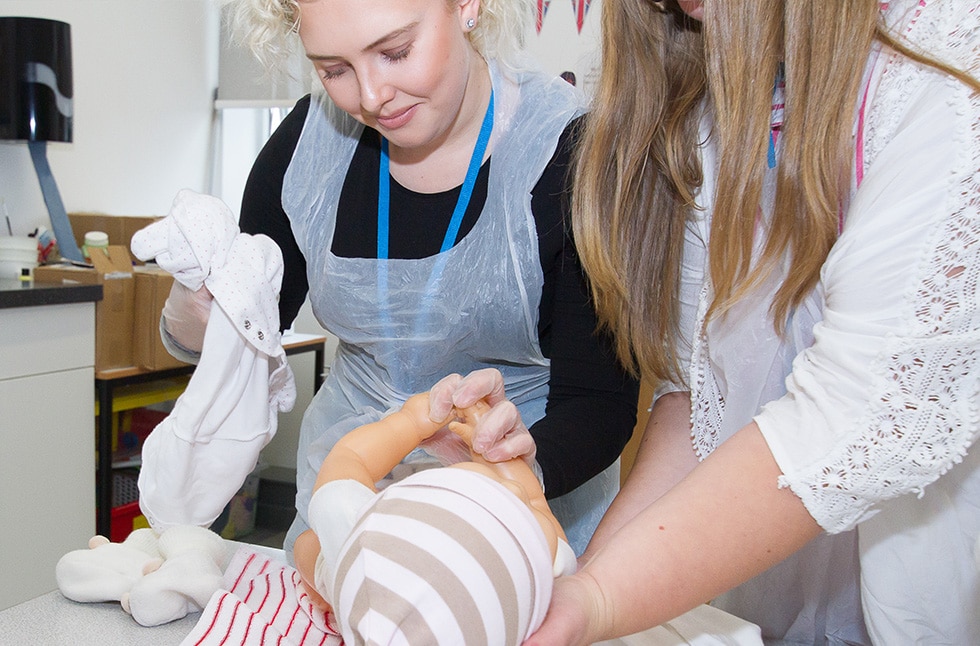 Students dressing a baby