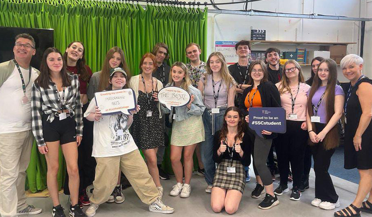Group photo of Performing Arts students and staff holding props