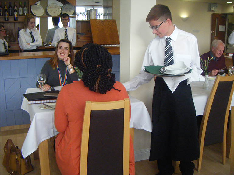 Student waiter serving customers in Perrcroft Restaurant