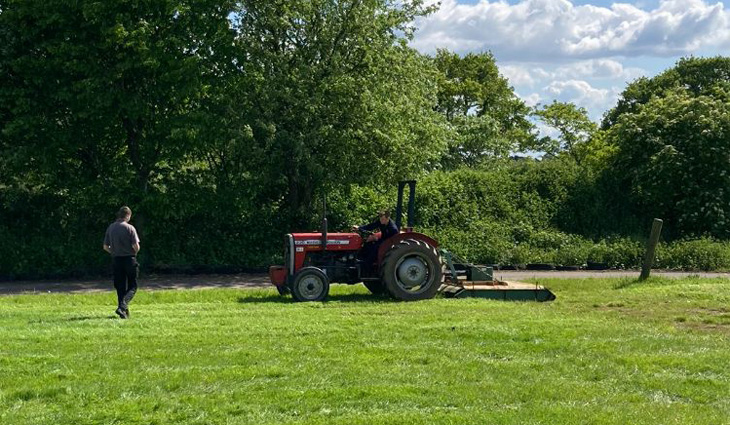 Agricultural engineering student operating Massey 230 tractor and topper on grass