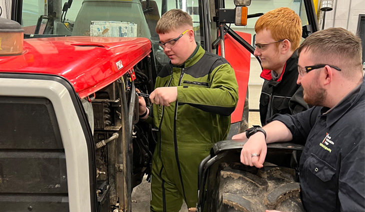 Three agricultural engineering students working on a tractor