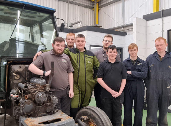 Group of Agricultural Engineering students standing by the side of a tractor