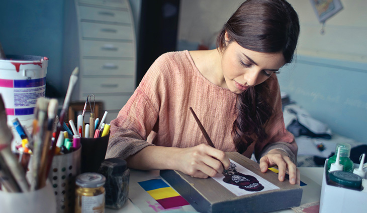 A female student in an art room painting a picture