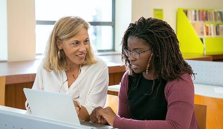 two adults talking and looking at laptop