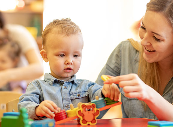 Child playing with toys on a table with a woman