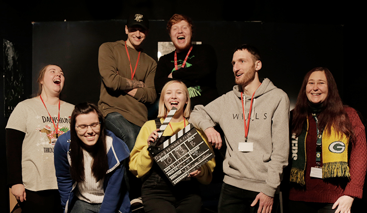 Group of 7 film and television students standing together laughing