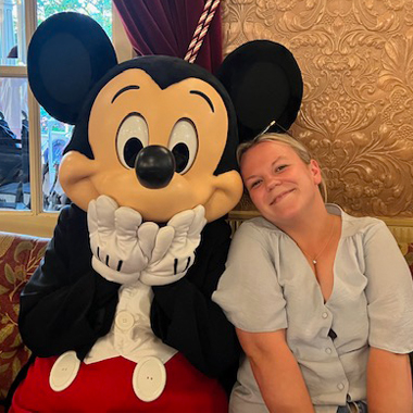 Photo of employability tutor Georgia Peake sat next to Mickey Mouse