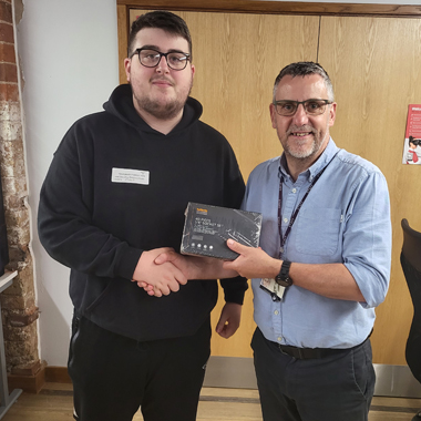 Student Harvey Binder-Jones shaking hands with, and receiving prize from, tutor Phillip Gooch