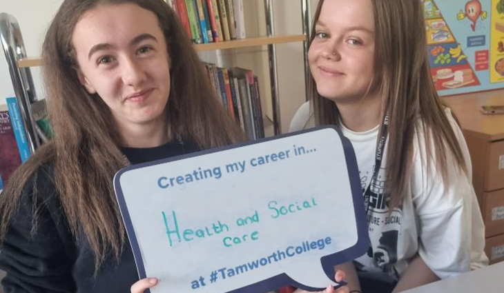Two Health and Social Care students holding selfie board
