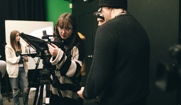 Photograph of TV, film and media students operating a camera