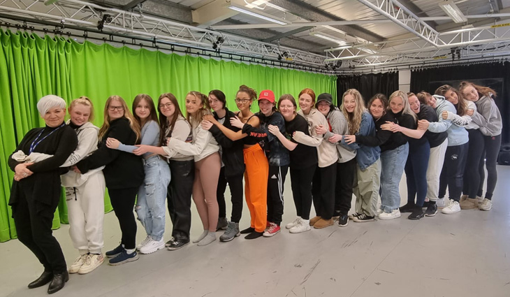 Photo of performing arts students standing in a line and hugging