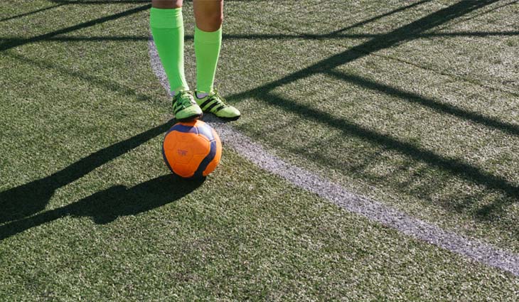 Person in Green Socks Stepping on Soccer Ball