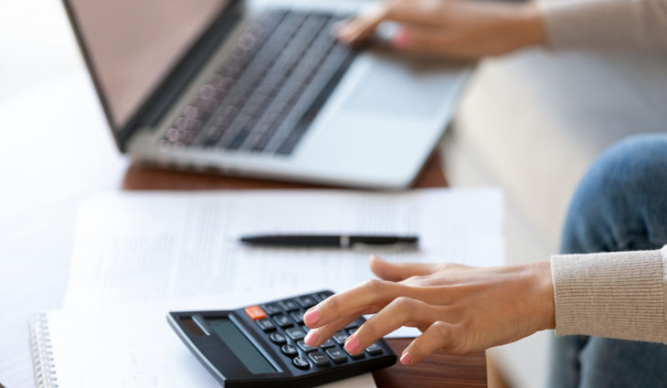 Person using calculator and laptop on table