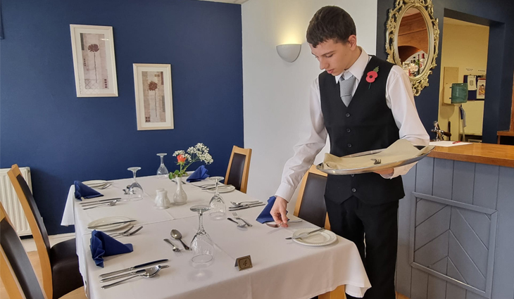 Photo of Hospitality student Tyler laying table in restaurant