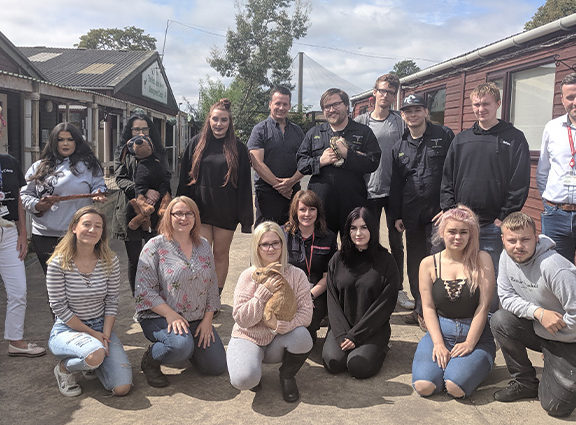 A group of staff and students smiling at camera holding animals