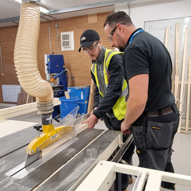 Carpentry student Rhys Thomas being shown machine by lecturer Dan Tucker