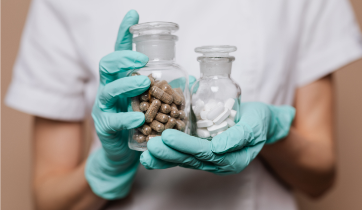 Person in gloves holding two jars of tablets