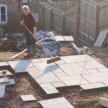 A landscape apprentice laying slabs in a garden