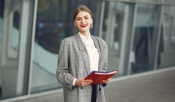 Happy female manager with papers near office building