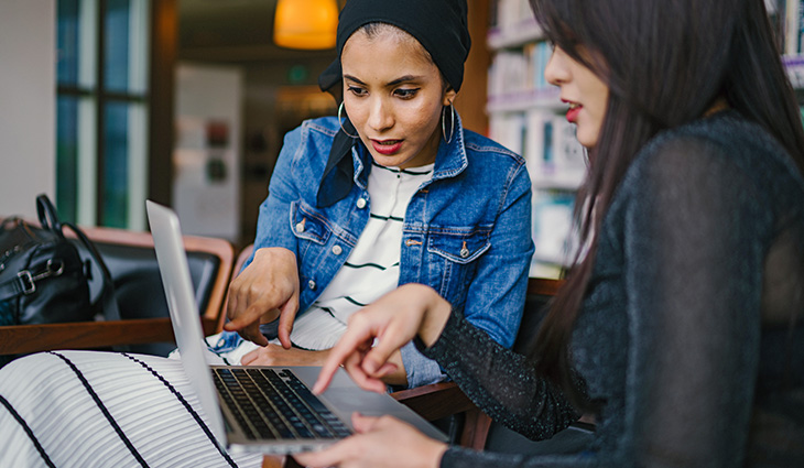 two female students looking at a laptop