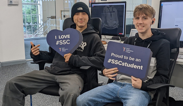 Photo of IT students sitting holding photo props