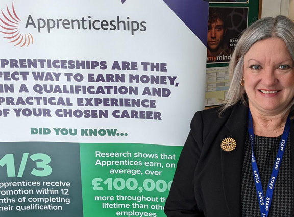 Karen Lees standing by apprenticeship banner at Job Fair