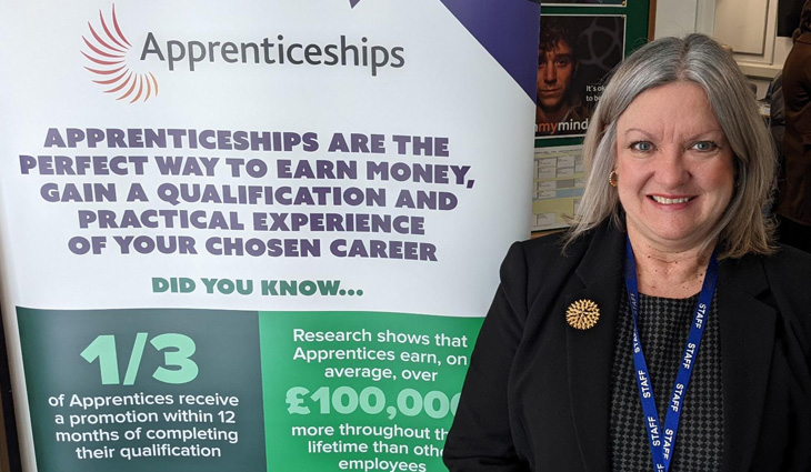 Karen Lees standing by apprenticeship banner at Job Fair