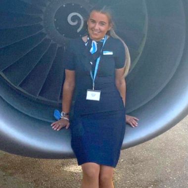 Photo of former Travel and Tourism student Lucy Kinson sitting in front of an aeroplane engine working for TUI