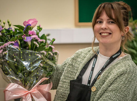 Photo of Floristry student Jade Owen holding a bouquet of flowers