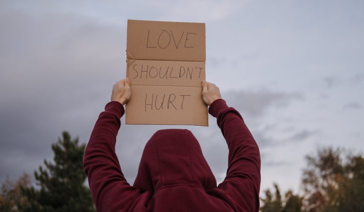Person Holding Love Shouldn't Hurt Sign