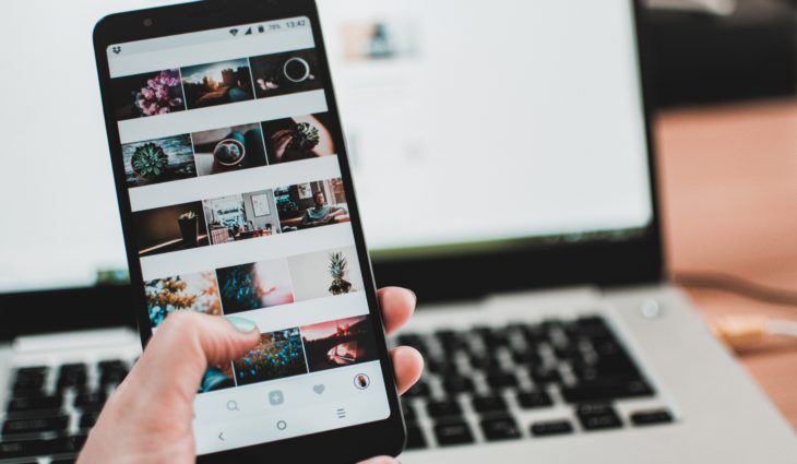 Person on social media on phone in front of laptop