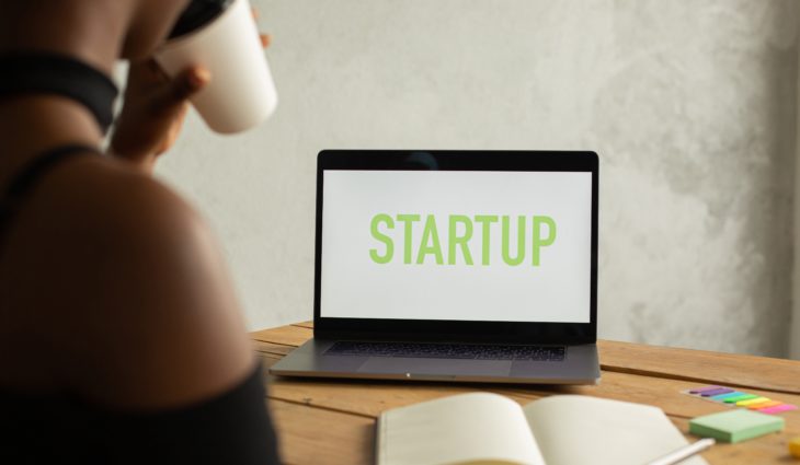 Person sitting in front of laptop screen that says Startup