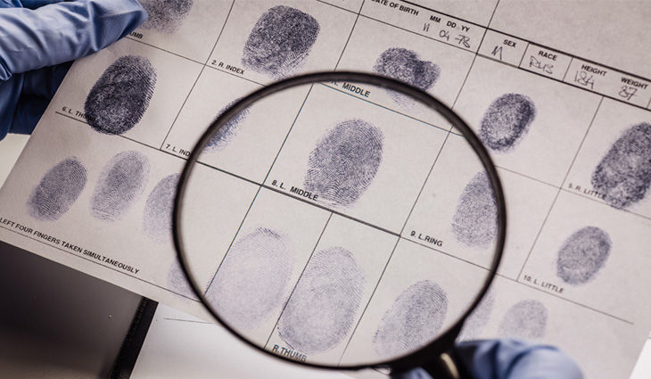 Magnifying glass looking at finger prints on a piece of paper
