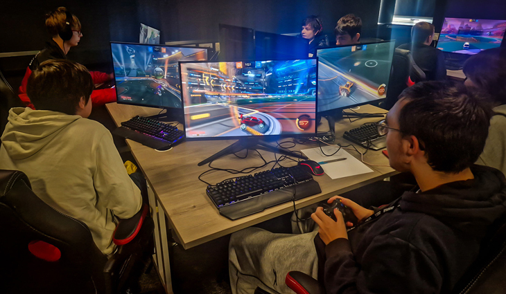 Photo of male gaming students playing Rocket League on computer screens in an Esports classroom