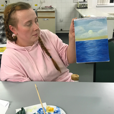 Photo of Ellie Gibson holding painting
