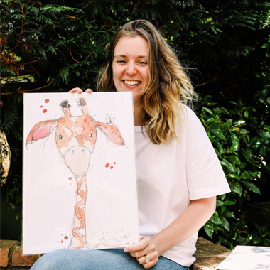 Photo of Community Lecturer Leah Riley holding illustration of giraffe