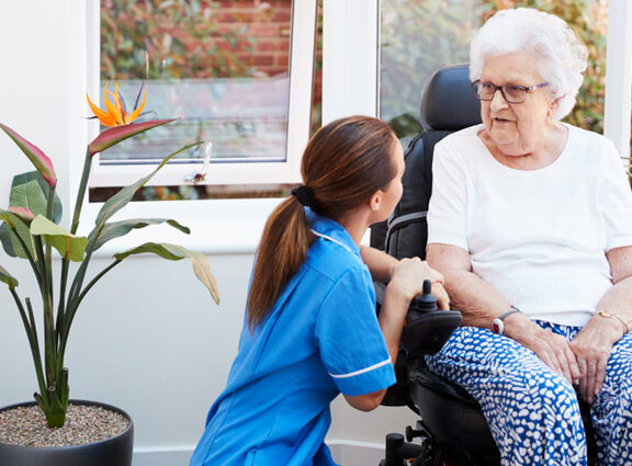 Photo of female adult care worker talking to elderly woman