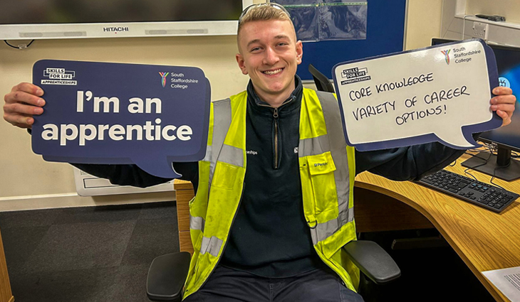 Photo of apprentice William James-Walker holding signs promoting apprenticeships